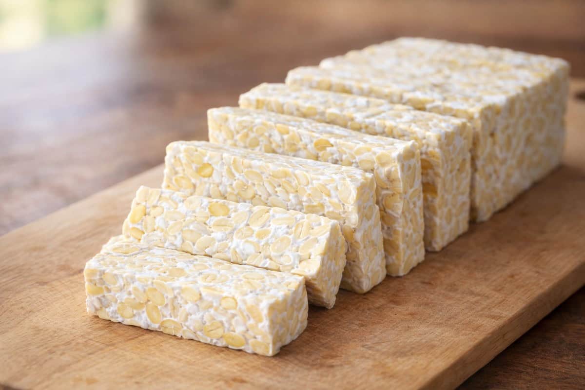 What is Artisanal Tempeh shown as sliced fresh tempeh on a wooden board, highlighting firm texture and whole soybeans.