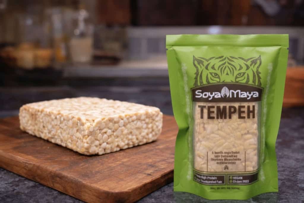 Soya Maya Tempeh on wooden cutting board with packaged tempeh in the foreground.