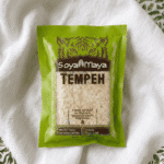 A green package of SoyaMaya Tempeh resting on a textured white cloth.