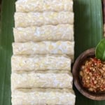 Sliced traditional Indonesian tempeh on banana leaf with sambal, representing the benefits of live culture tempeh