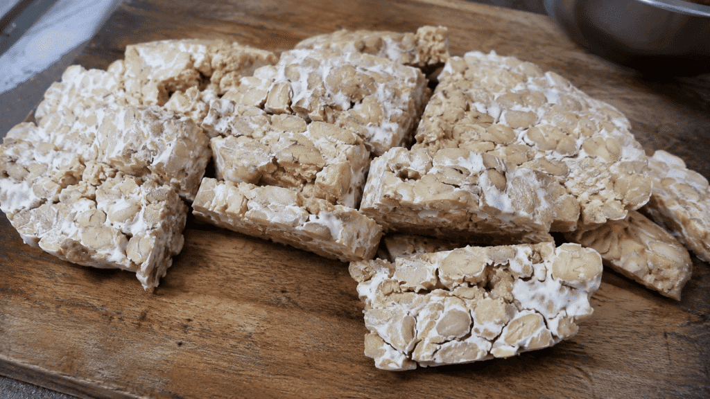 Sliced tempeh blocks on a wooden board, controlling what temperature for tempeh fermentation gives this nutty texture.